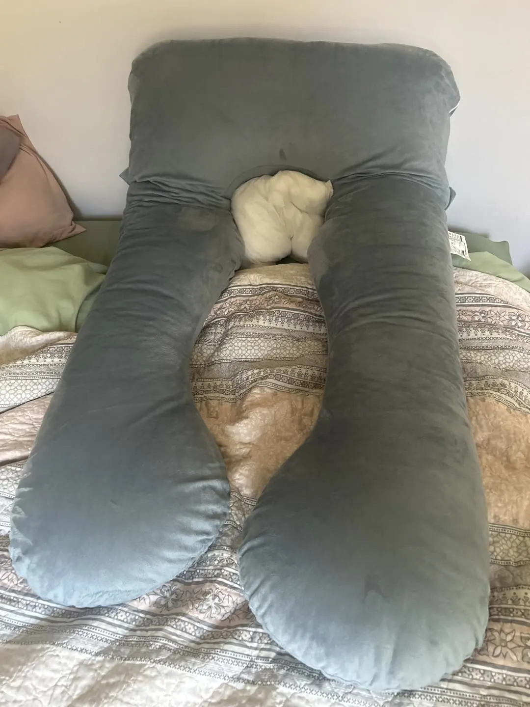 The U-shaped bamboo pregnancy pillow laid out on a bed.